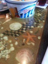 How cool is this? Seashells and beach sand are layered under the table tops.
